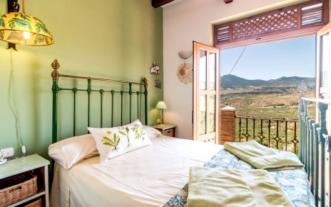 Habitación en el primer piso con cama doble y balcón.